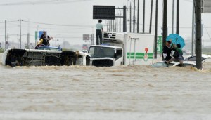 People wait for help as the vehicles are submerged in flooding in Joso, Ibaraki prefecture, northeast of Tokyo Thursday, Sept. 10, 2015. Heavy rain is pummeling Japan for a second straight day, overflowing rivers and causing landslides and localized flooding in the eastern part of the country. (Kyodo News via AP) JAPAN OUT, MANDATORY CREDIT